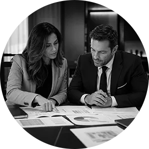 Profissionais analisando documentos de uma operação empresarial em preto e branco.